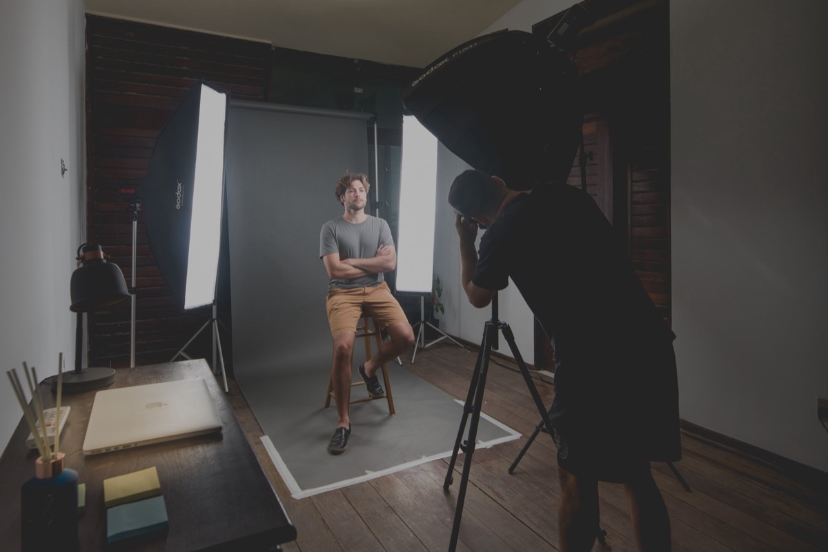Fotógrafo fotografando um modelo sentado no estúdio, entre softboxes
