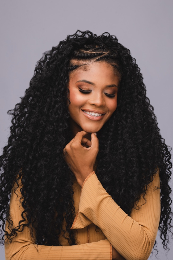 Mulher de cabelo cacheado sorrindo, fundo escuro
